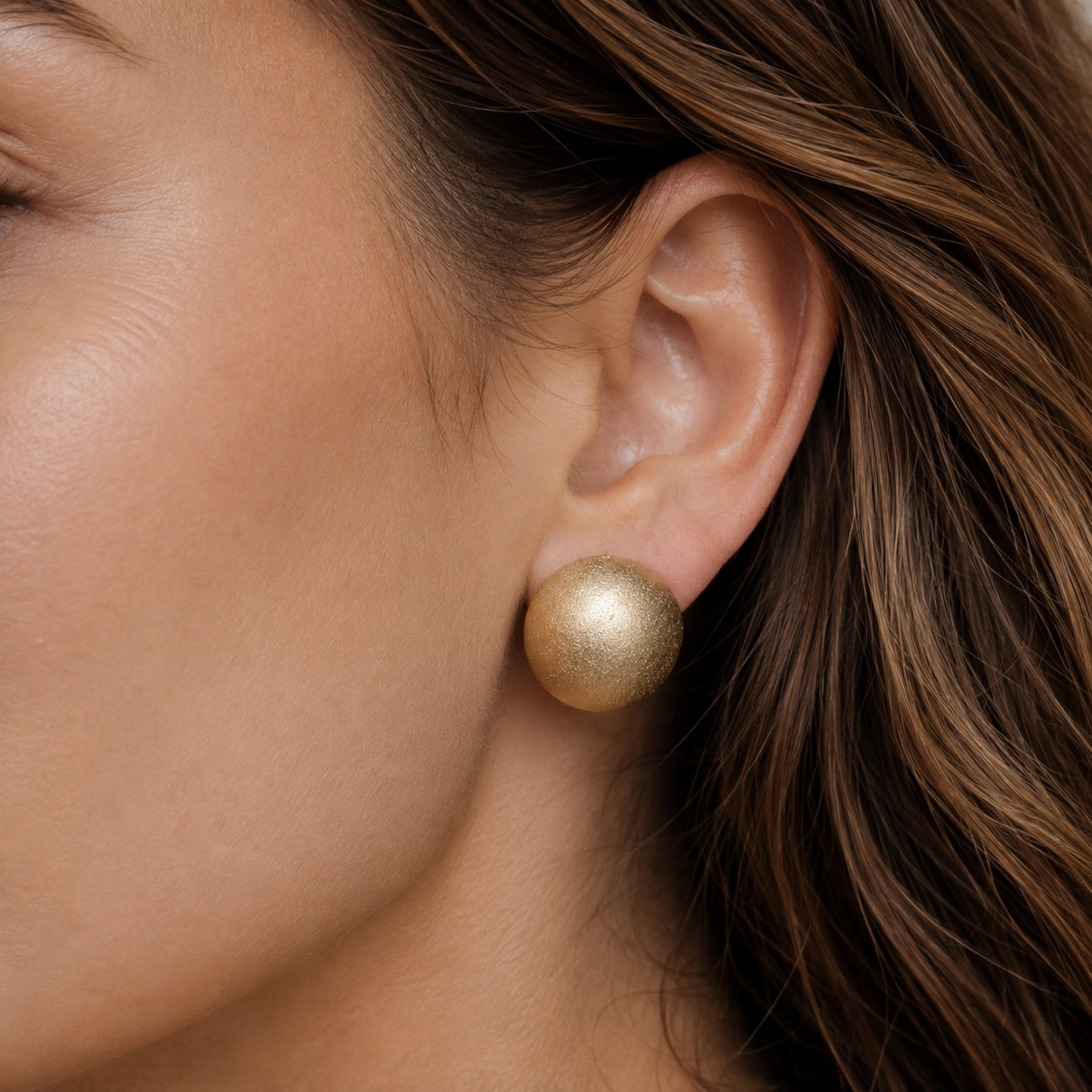 Time4Me gold matte half-sphere stud earrings worn on a woman's ear, crafted from durable stainless steel.