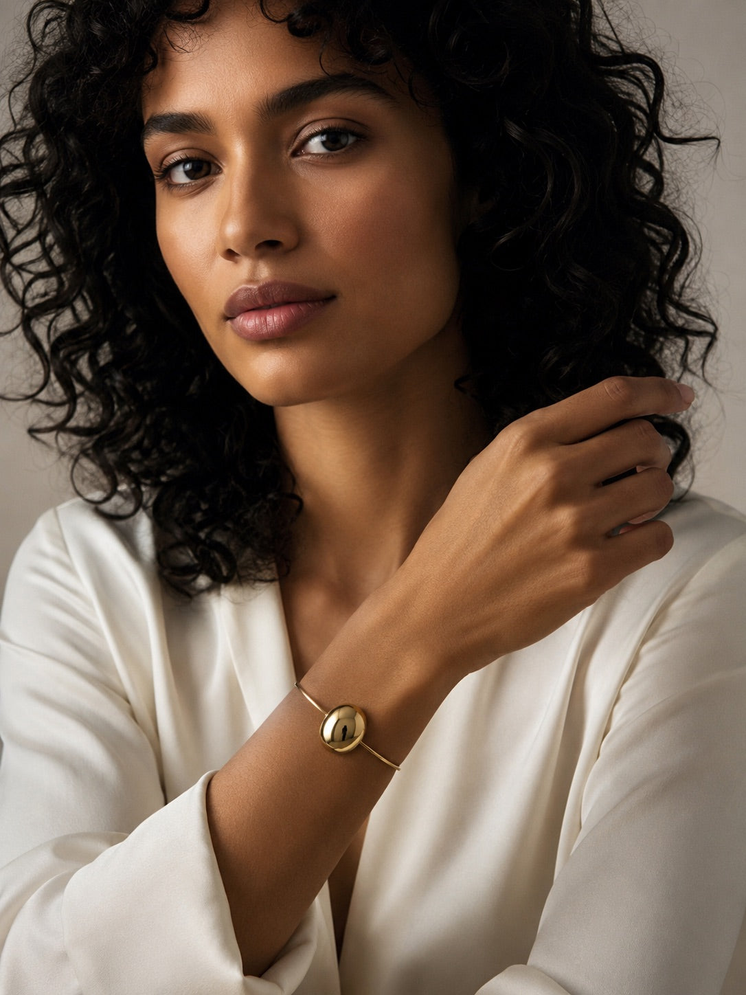 Time4Me gold open cuff bracelet with a smooth round charm worn by a woman in a white blouse