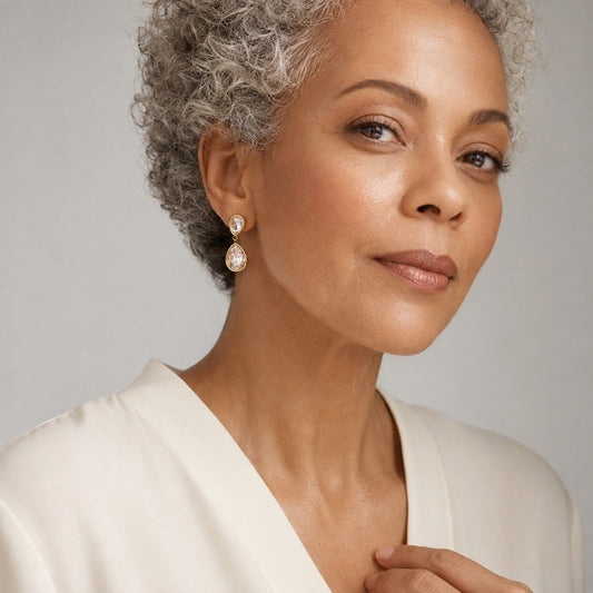 Time4Me long gold stainless steel earrings with two clear glass teardrop pendants worn by a mature woman