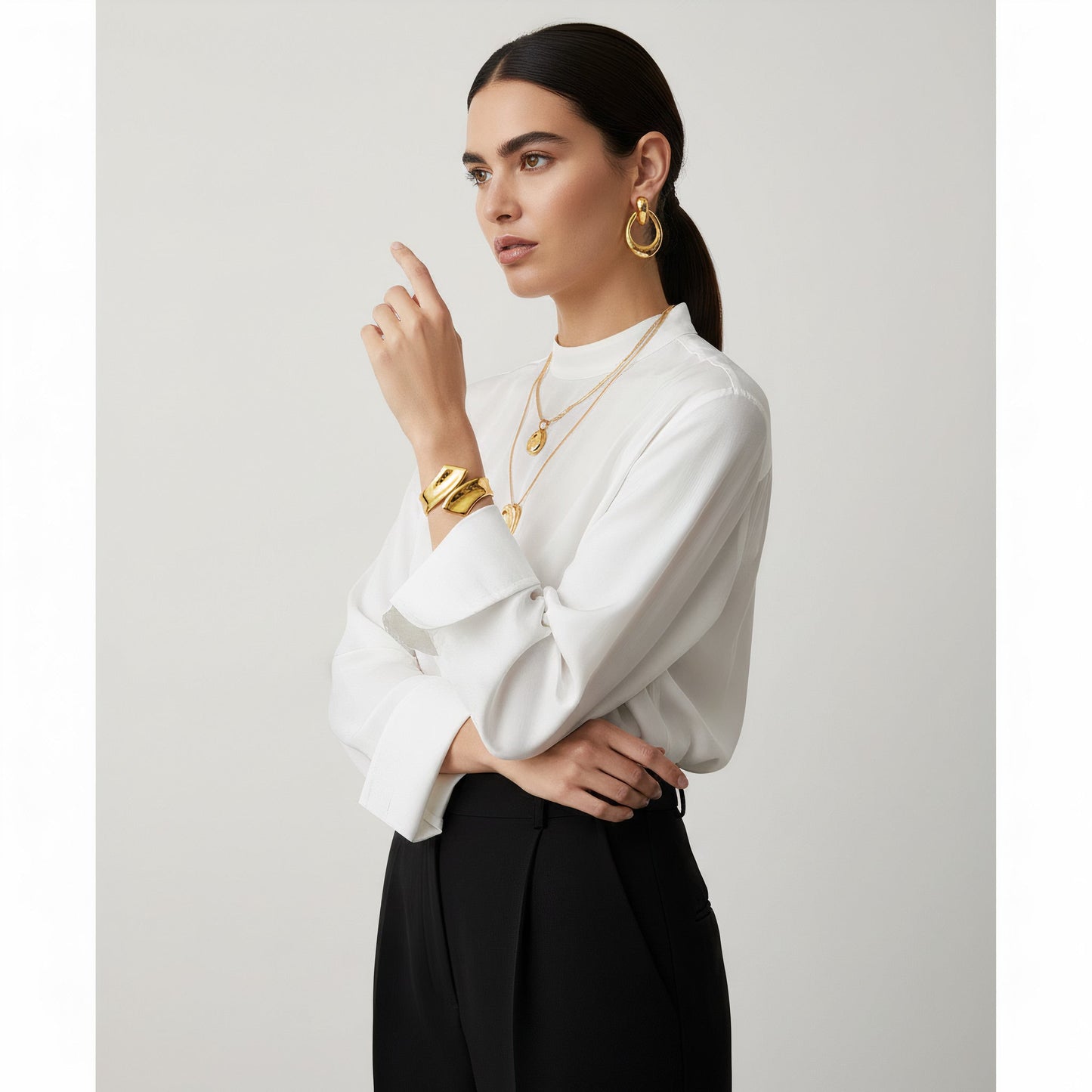 Time4Me sculptural gold open cuff bracelet worn by a model in a white blouse and black trousers