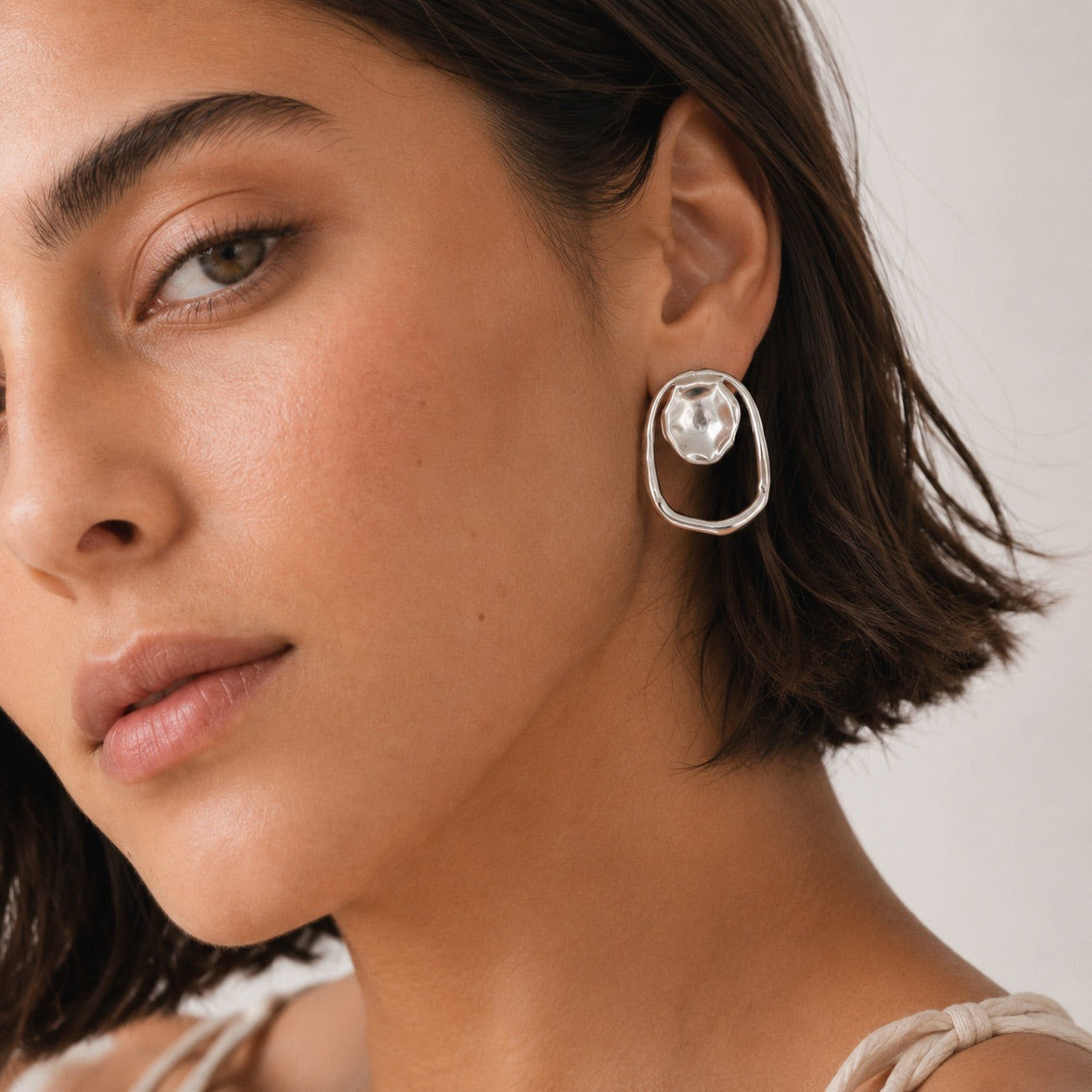Time4Me silver geometric earrings featuring a hammered circle and irregular mirror-effect ring on a woman