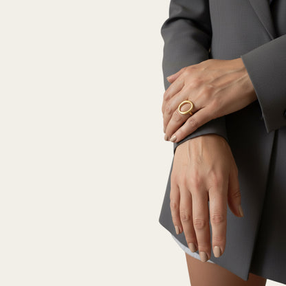 Time4Me adjustable gold oval ring with a brushed finish worn on a woman's hand with a grey blazer