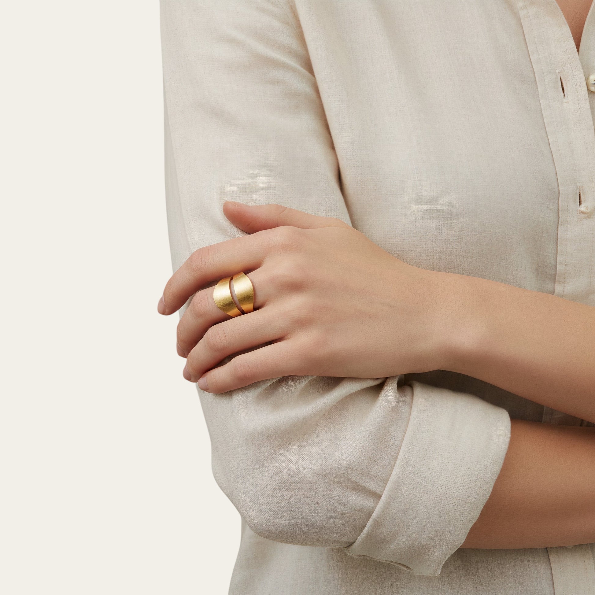 Time4Me adjustable gold-toned brushed stainless steel ring worn on a woman's finger with a beige linen shirt