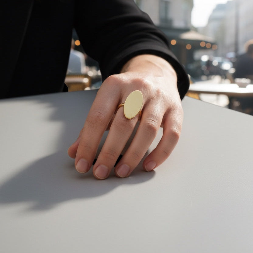 Time4Me adjustable gold-tone stainless steel oval ring worn on a woman's finger in an outdoor cafe setting