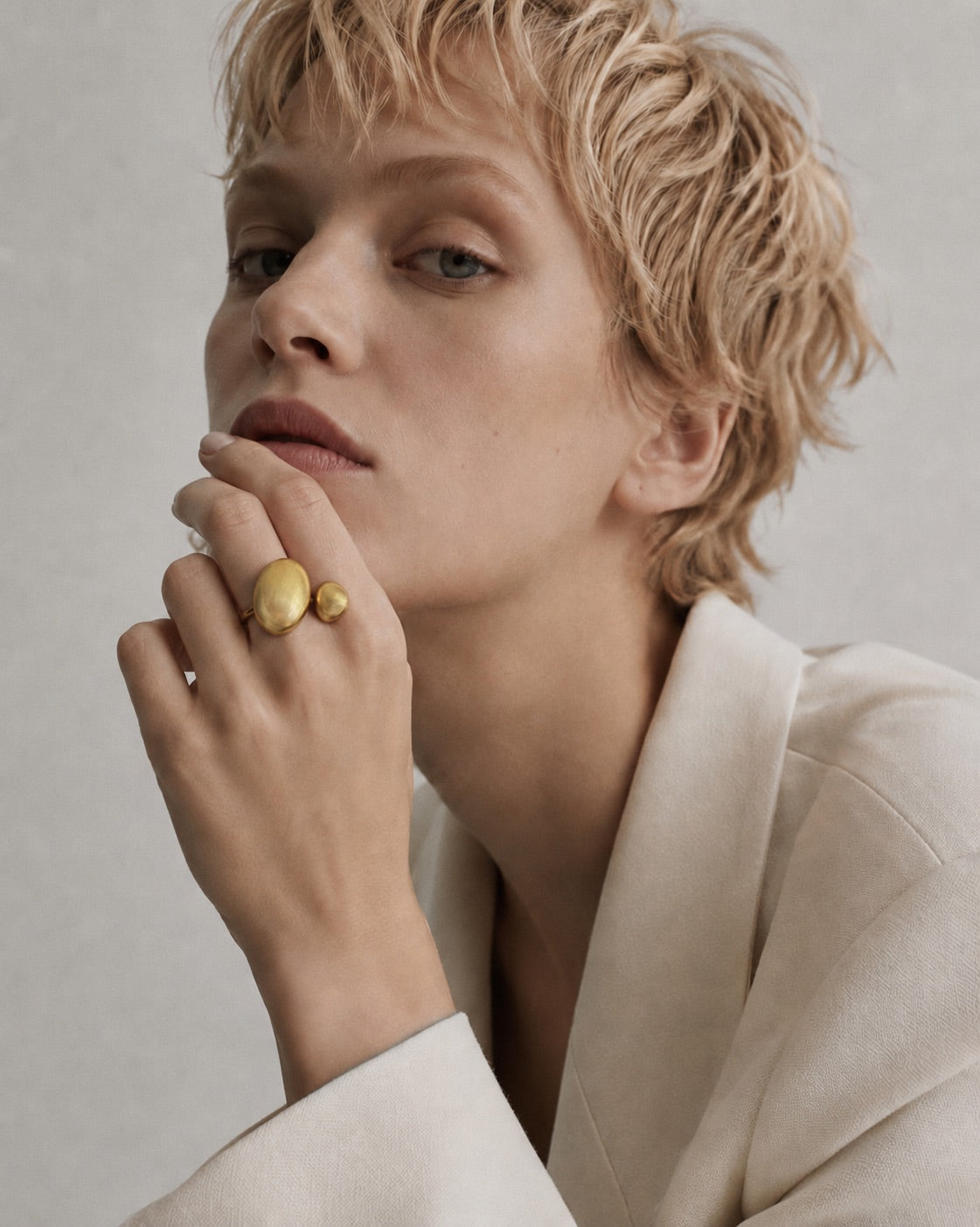 Time4Me gold adjustable ring with asymmetric brushed finish domes worn by a model in a white blazer