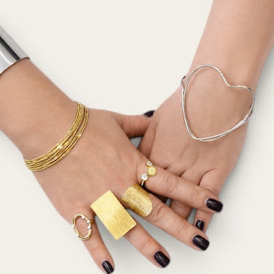 Time4Me gold chain bracelet worn on a hand with silver cuffs and various textured gold rings