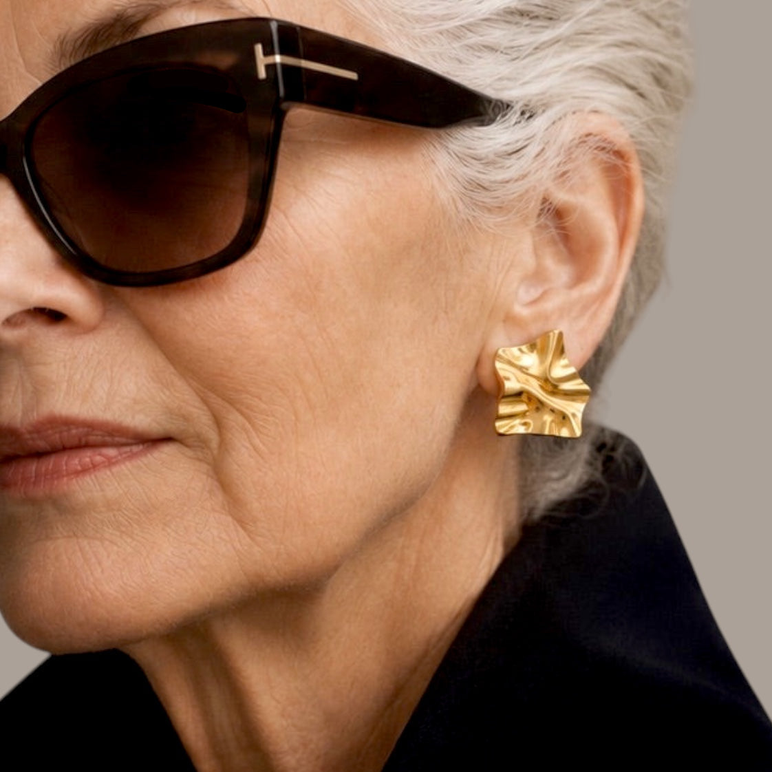 Time4Me gold geometric earrings with a textured crinkled finish worn by a woman in a black blazer and sunglasses.