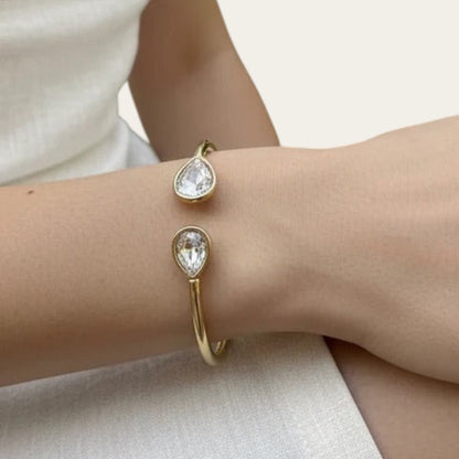 Time4Me gold stainless steel adjustable cuff bracelet featuring two teardrop-shaped glass crystals on a woman's wrist