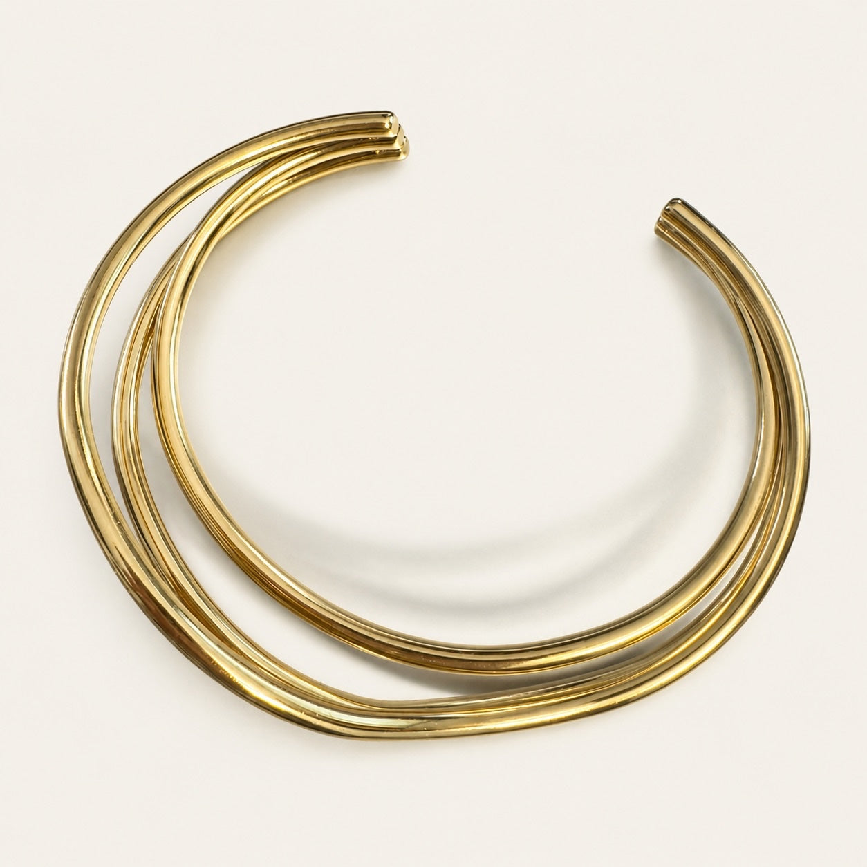 Time4Me gold-tone stainless steel cuff bracelet with a layered, crossed-line design on a white background.