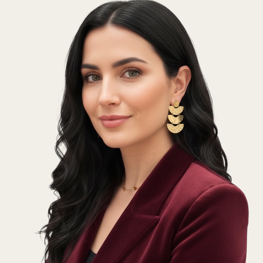 Time4Me gold chandelier earrings with hammered semicircular layers worn by a woman in a burgundy velvet blazer