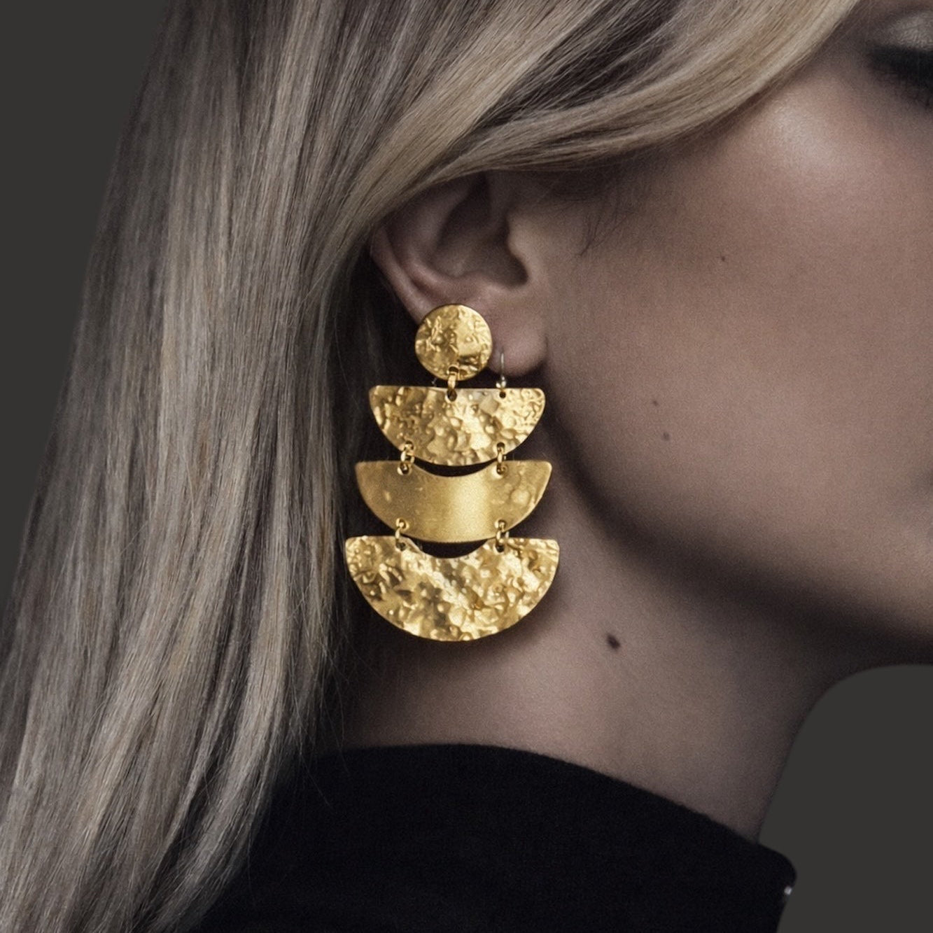 Time4Me gold chandelier earrings featuring stacked hammered semicircles in stainless steel worn by a woman