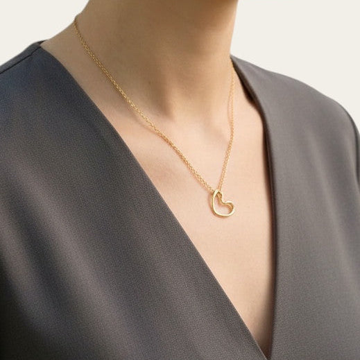 Time4Me gold stainless steel necklace featuring a minimalist stylized heart pendant worn by a woman