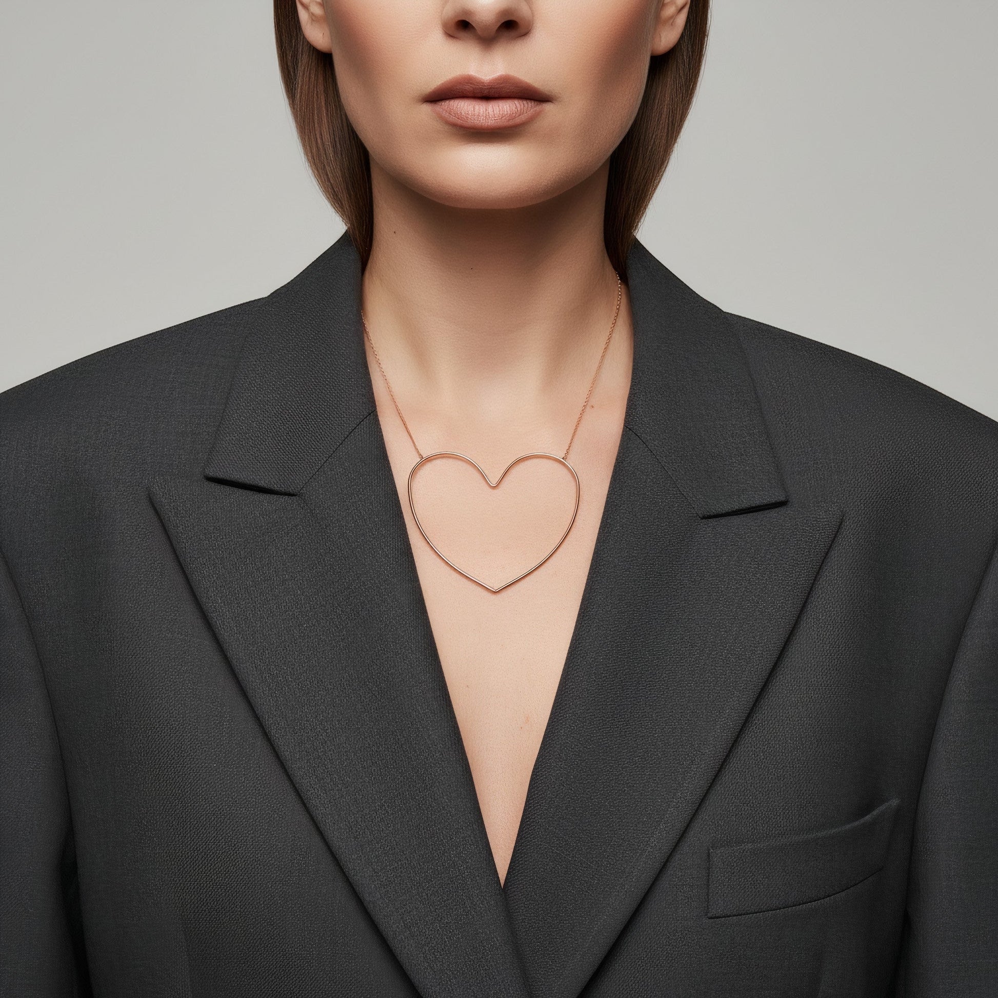 Time4Me gold-toned stainless steel necklace with a stylized open heart pendant worn over a dark grey blazer