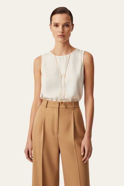 Time4Me long gold stainless steel necklace with asymmetric knots worn by a model in a white top and beige trousers