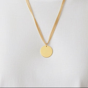 Time4Me gold layered necklace with a round engraving pendant worn by a woman in a white t-shirt