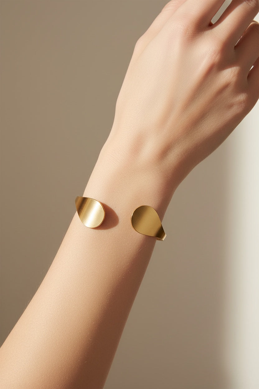 Time4Me gold-tone stainless steel open cuff bracelet with teardrop-shaped ends worn on a woman's wrist