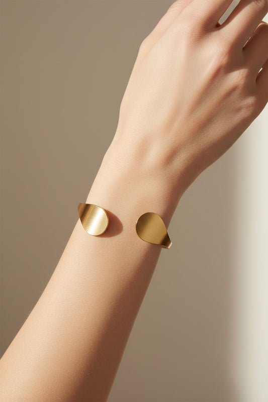 Time4Me gold-tone stainless steel open cuff bracelet with teardrop-shaped ends worn on a woman's wrist