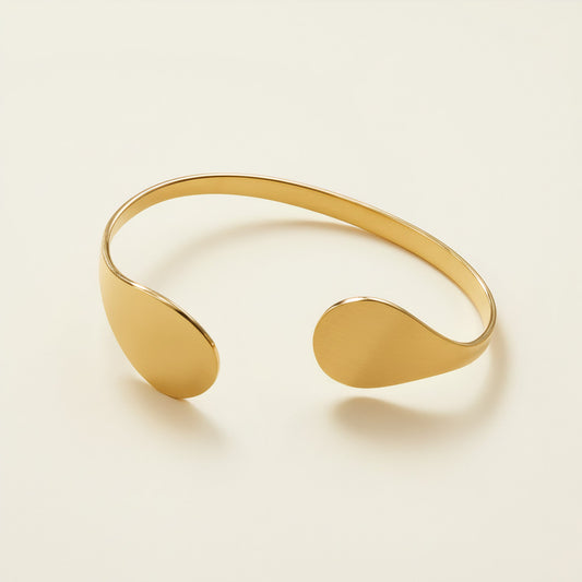 Time4Me gold-toned stainless steel open cuff bracelet with teardrop-shaped ends on a neutral background.