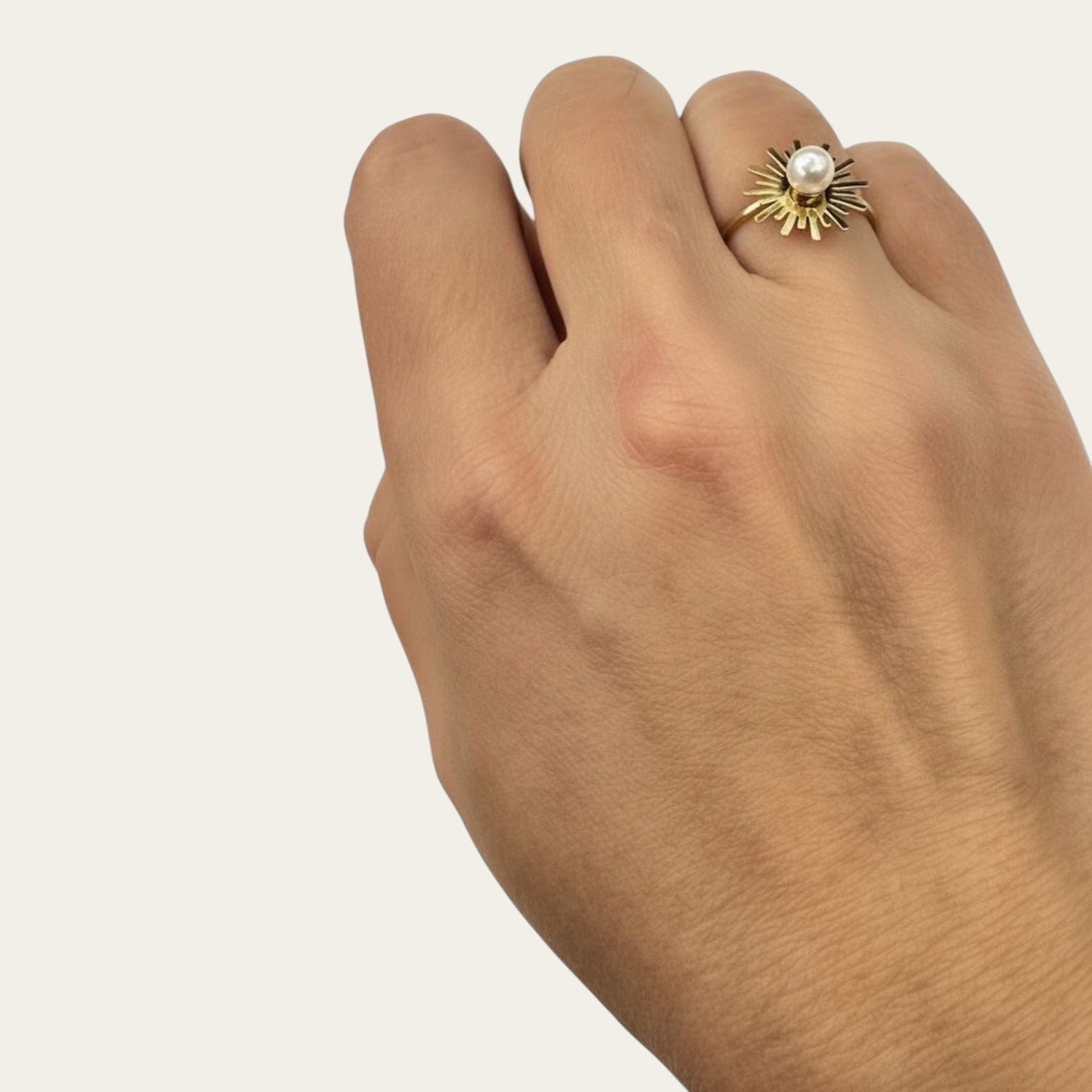 Time4Me adjustable gold-tone stainless steel ring featuring a sunburst design and a central white pearl on a hand.