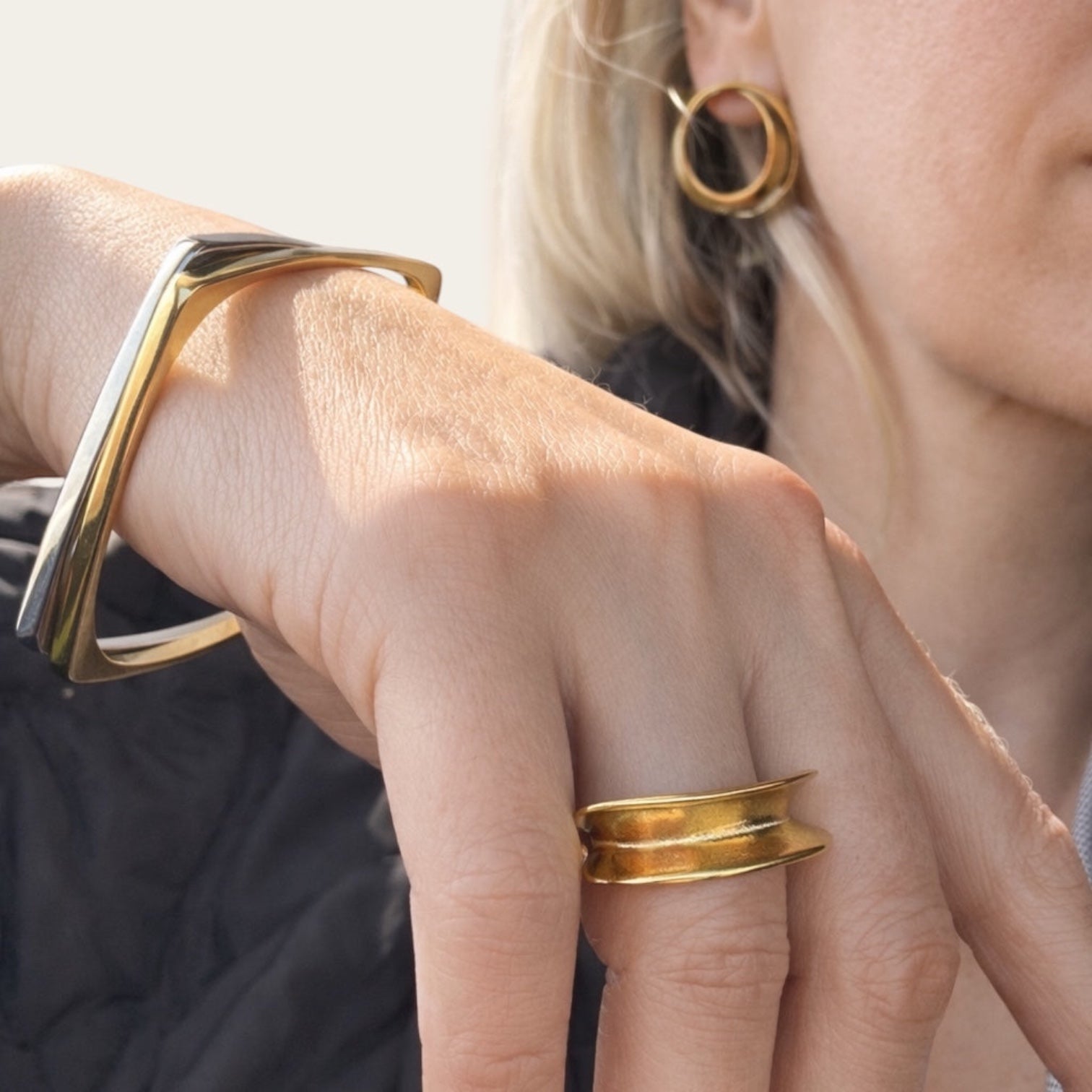 Time4Me gold wave ring made of stainless steel worn on a finger with a matching gold bangle and hoop earrings