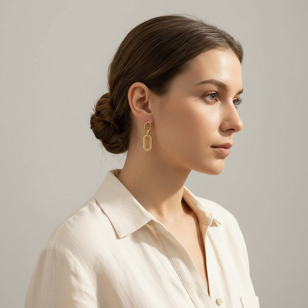 Time4Me long gold-tone stainless steel earrings with textured chain links worn by a woman with a sleek hair bun