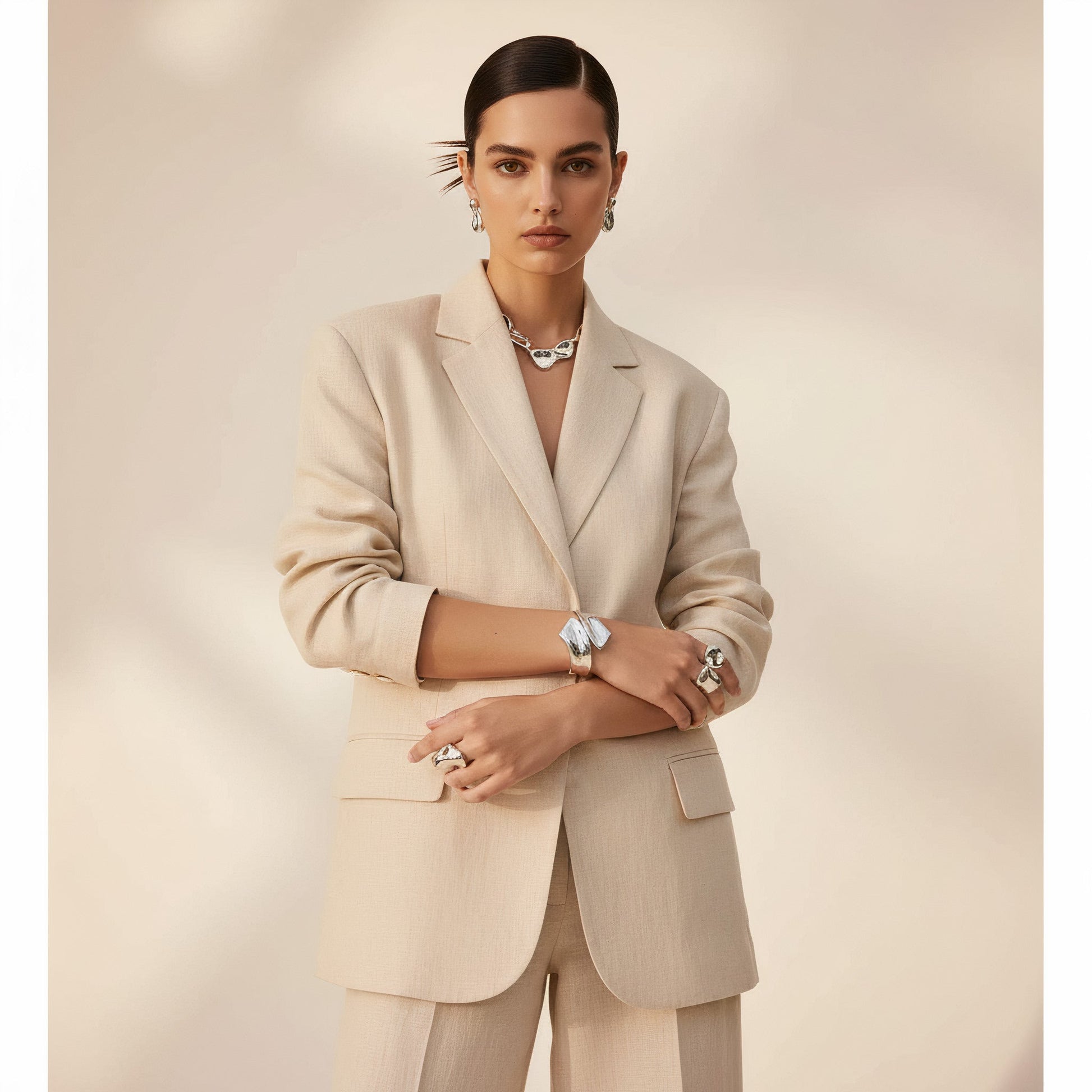 Time4Me sculptural silver open cuff bracelet worn by a model in a beige suit for a modern, elegant look.