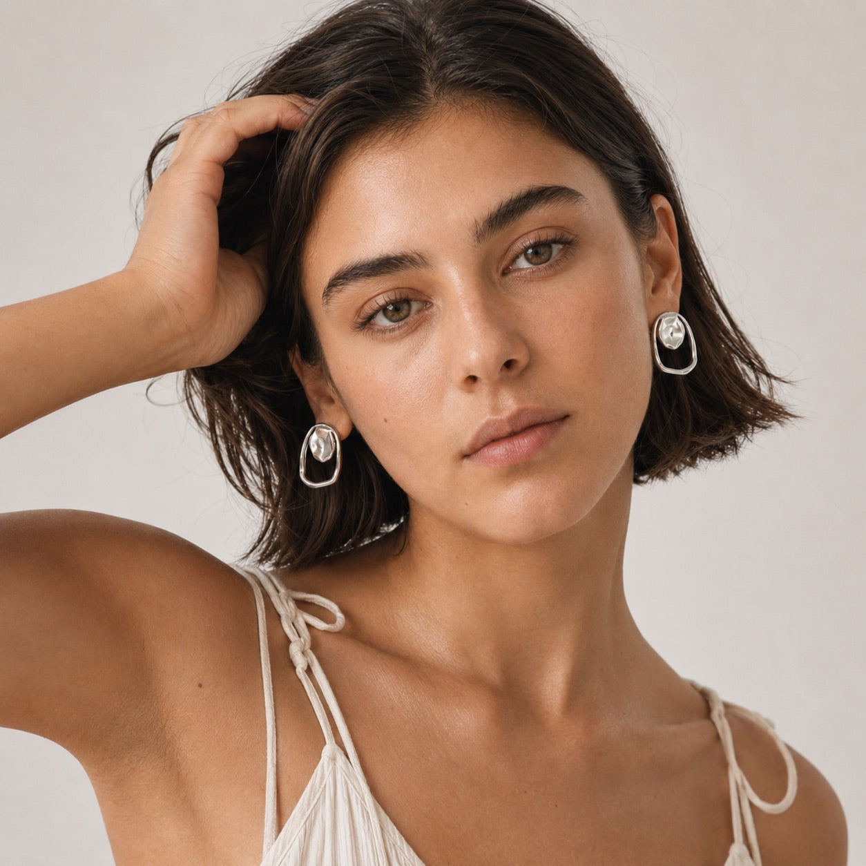 Time4Me silver geometric earrings with hammered circle and irregular mirror-effect ring worn by a woman