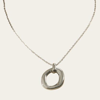 Time4Me silver-toned stainless steel necklace featuring a polished oval pendant with a relief design on a fine chain.