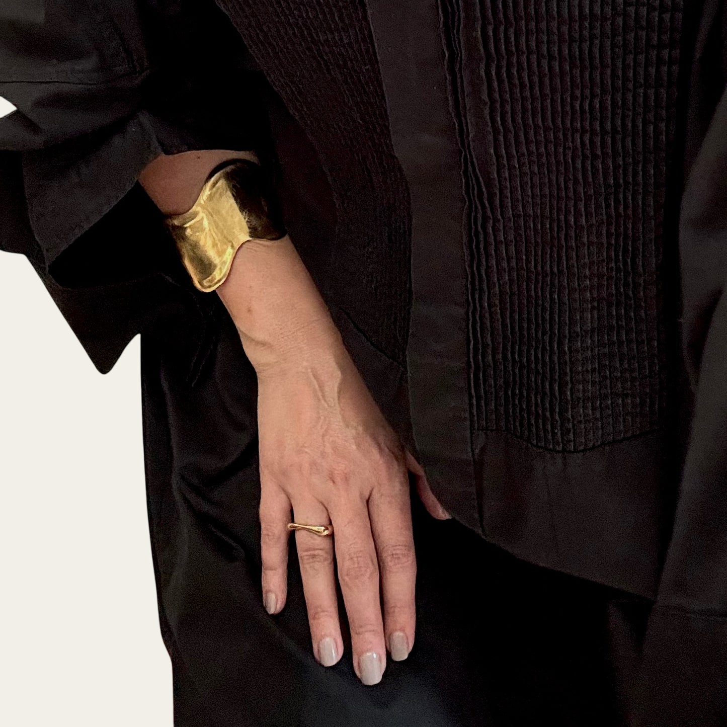 Time4Me wide gold cuff bracelet with a brushed wave design worn on a woman's wrist against a black outfit